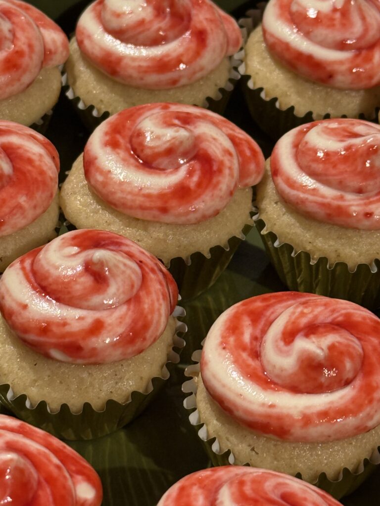 Vanilla cupcakes with raspberry cream cheese frosting that is swirled on top!